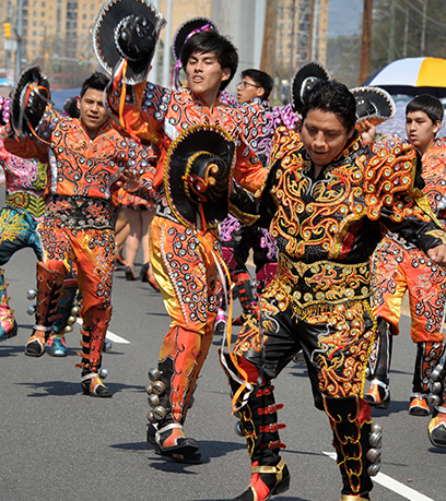 Hombres con trajes tradicionales se mueven dinámicamente en la calle en un desfile.