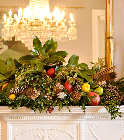 Un manto está decorado con hojas de magnolia, plumas, frutas, bayas de acebo y más.